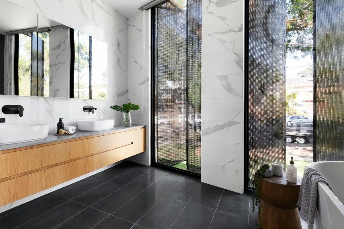 A bathroom with a large window and black tile floor.